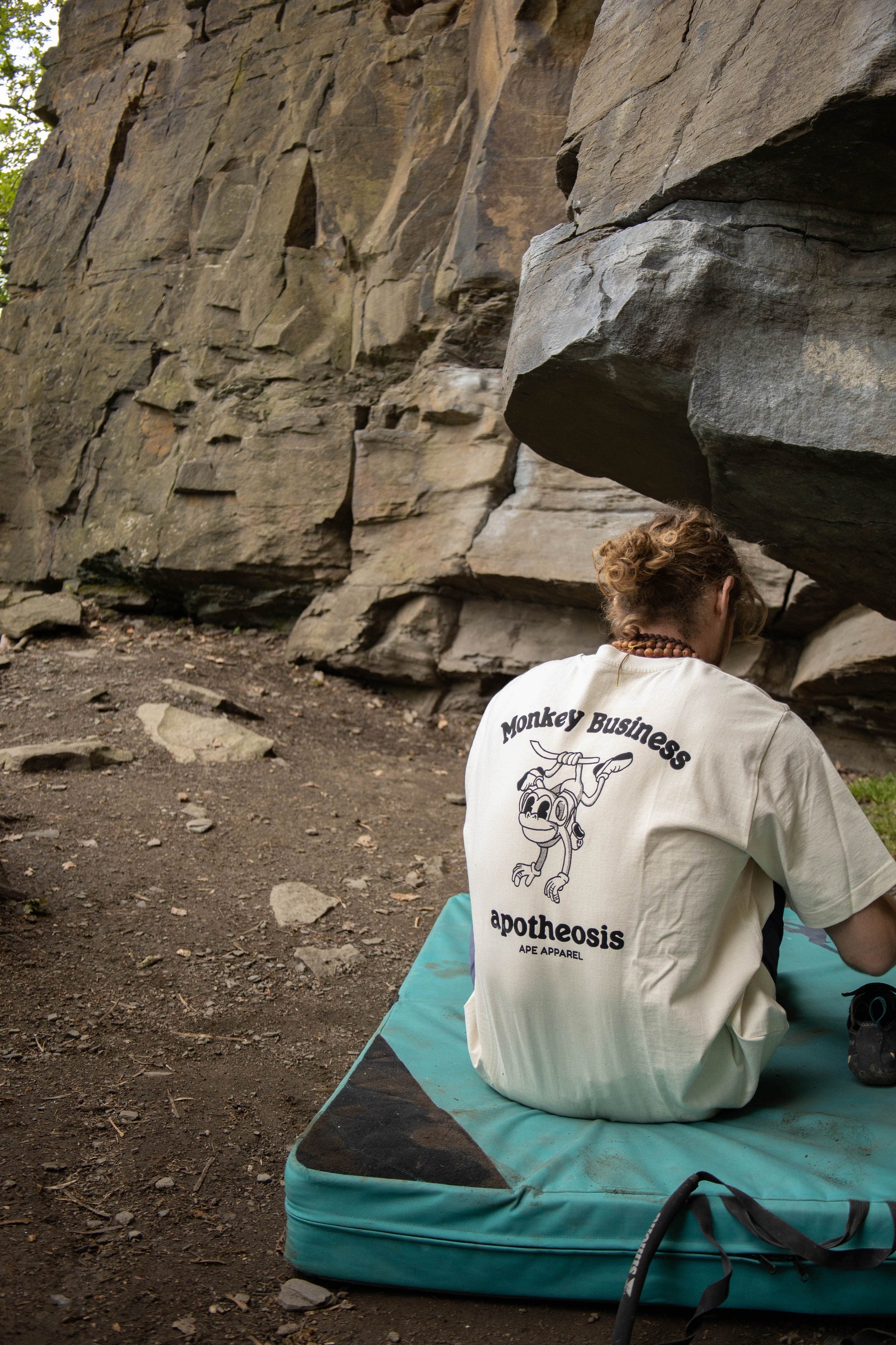 Back of Monkey Business Tee in front of real rock. Model is wearing an L